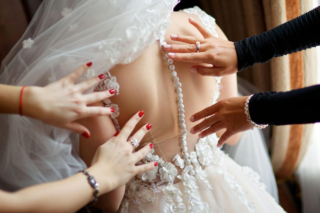 Bride being assisted into wedding dress by professional bridal dresser