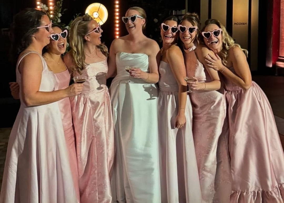 Bride and bridesmaids in formal dresses with sunglasses at a wedding