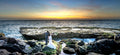Couple standing on rocky beach at sunset