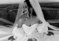 Woman in a wedding dress with a veil, sitting on a boat.