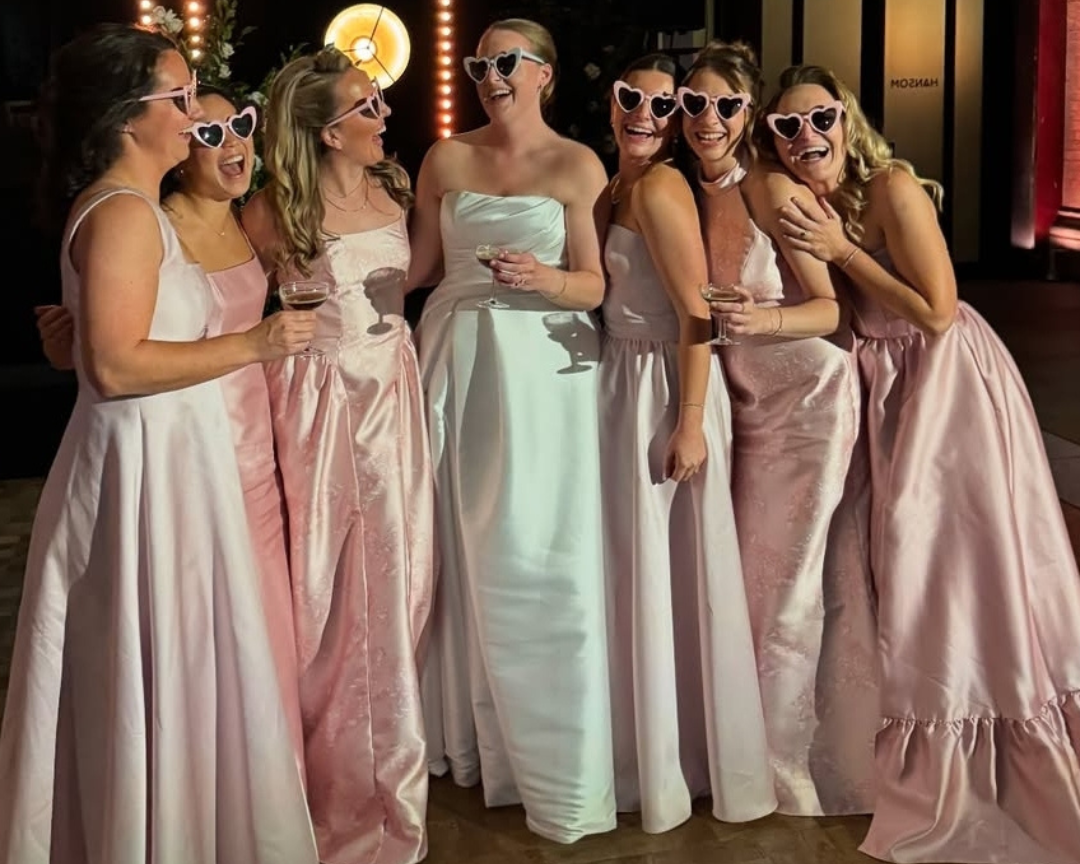 Group of women in formal dresses with sunglasses at a formal event.